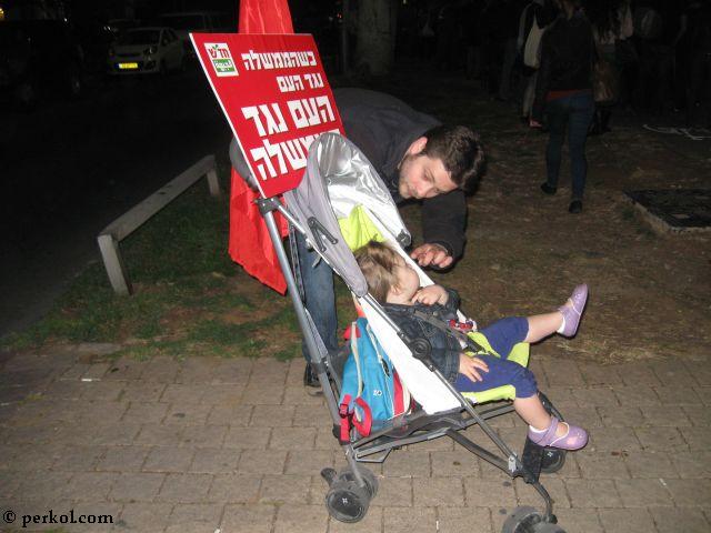 תינוקת בעגלה ושלט מחאה