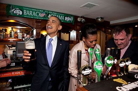 נשיא ארצות הברית, ברק אובמה, משוחח עם באי הפאב, בעוד הגברת הראשונה, מישל אובמה, מוזגת כוסית בירה עם אולי הייז, בפאב של אולי הייז, במוניגול, אירלנד. תמונה: פליקר הבית הלבן, משוחרר מזכויות יוצרים