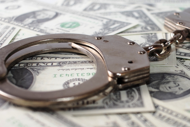 A closeup shot of metal handcuffs and dollars
