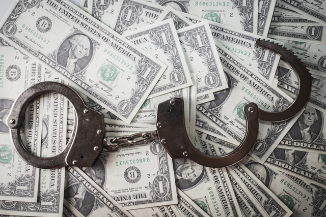 A closeup shot of metal handcuffs and dollars